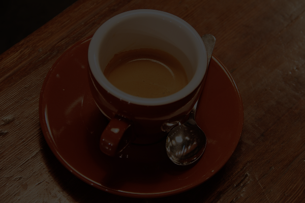 The dark coffee-cup image and the toy network's output, which is much brighter, with visible wood grain and a lighter, slightly greenish and less saturated color than the original photo.